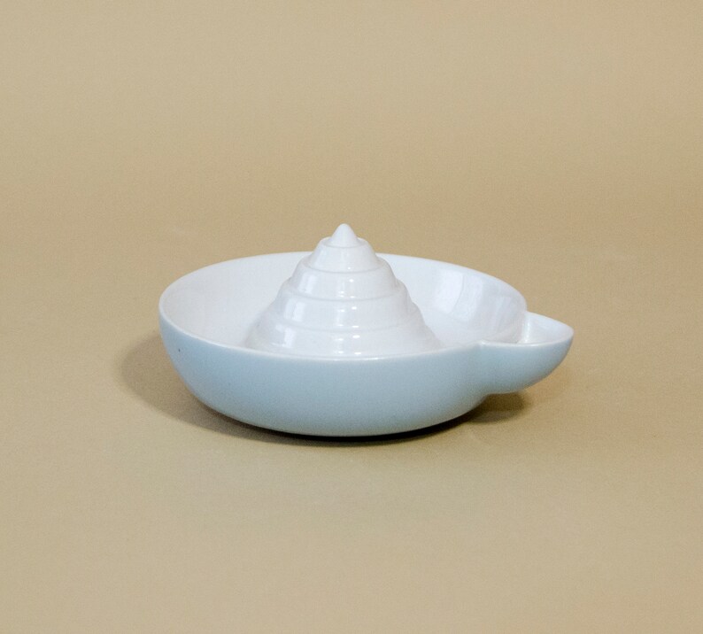 May include: A white ceramic citrus juicer with a light blue base. The juicer has a cone-shaped reamer with ridges for squeezing lemons and limes.