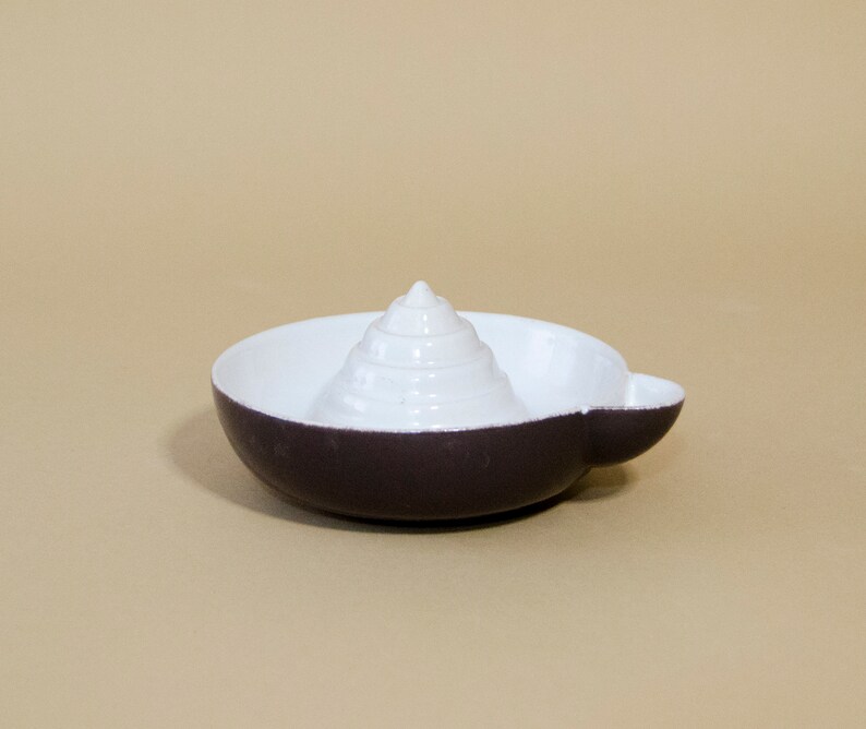 May include: A white and dark gray ceramic citrus juicer with a cone-shaped reamer in the center.