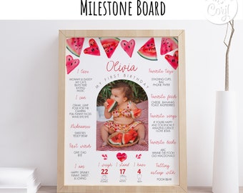 Könnte beinhalten: Ein personalisiertes Meilenstein-Board mit einem Wassermelonen-Thema. Das Board zeigt ein Foto eines kleinen Mädchens sowie Details zu ihrem ersten Lebensjahr, darunter ihr Gewicht, ihre Größe und die Anzahl ihrer Zähne. Das Board ist mit rosa Herzen und Wassermelonenstücken verziert.
