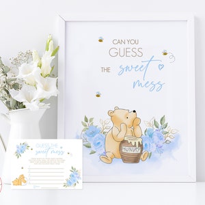 Puede incluir: Una tarjeta de juego de baby shower con temática de Winnie the Pooh con acentos florales azules y amarillos. La tarjeta dice "Adivina el dulce desastre" y presenta un dibujo animado de Winnie the Pooh sosteniendo un tarro de miel.