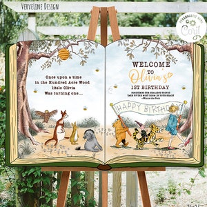 K&ouml;nnte beinhalten: Ein Winnie-the-Pooh-Geburtstagsschild mit einem buchf&ouml;rmigen Design. Das Schild enth&auml;lt ein Zitat von Winnie the Pooh und eine Willkommensnachricht f&uuml;r Olivias 1. Geburtstag. Das Schild ist mit Illustrationen von Winnie the Pooh und seinen Freunden verziert.