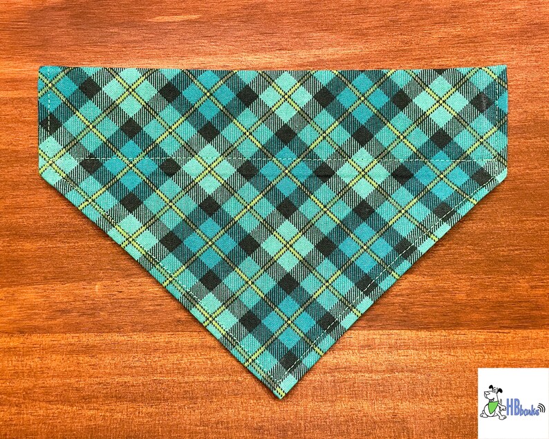 May include: A turquoise, black, and yellow plaid dog bandana. The bandana is triangular in shape and has a stitched edge.