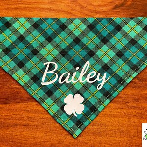 May include: A green and black plaid dog bandana with a white shamrock and the name "Bailey" printed on it.