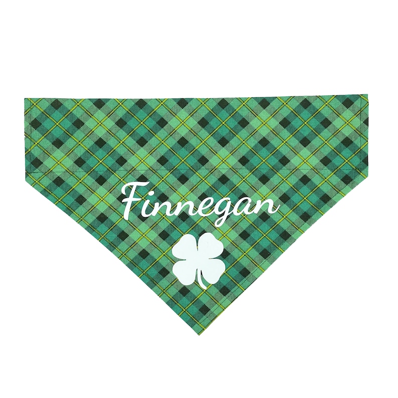 May include: Green and yellow plaid dog bandana with a white shamrock and the name "Finnegan" in white cursive.