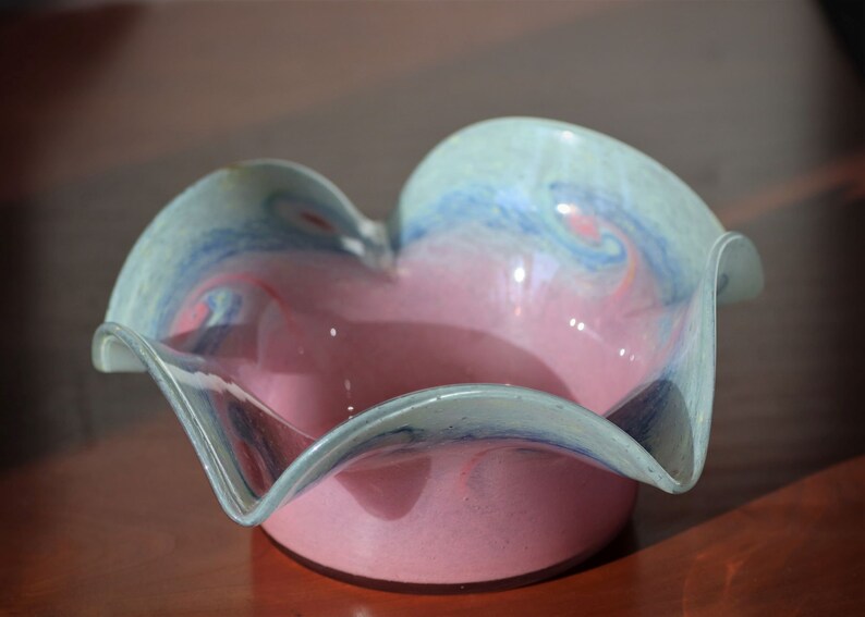 Może przedstawiać: R&oacute;żowa szklana miska z falistym, pofalowanym brzegiem. Miska ma wz&oacute;r w niebiesko-białe wiry.