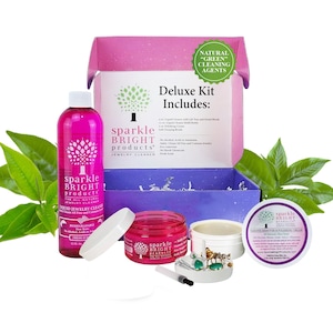 May include: A deluxe jewelry cleaning kit with a pink bottle of liquid cleaner, a jar of polishing cream, and a tarnish remover. The kit includes a lift tray and detail brush, and is advertised as using natural cleaning agents.