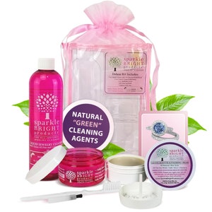May include: A pink and white jewelry cleaning kit with a bottle of liquid cleaner, a jar of polishing cream, a small brush, and a cleaning tray. The kit is packaged in a pink organza bag and includes a card with the text "sparkle bright products" and "Deluxe Kit Includes:".
