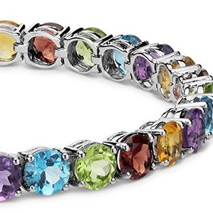 Puede incluir: Una pulsera de plata con una fila de piedras preciosas de colores. Las piedras est&aacute;n engastadas en una banda de plata y est&aacute;n dispuestas en un patr&oacute;n de arco&iacute;ris. La pulsera es una pieza de joyer&iacute;a hermosa y &uacute;nica.