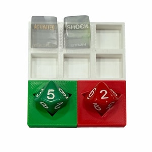 May include: A white, green, and red dice tray with two clear game pieces and two polyhedral dice. The dice are green with a 5 and red with a 2. The clear pieces have the words "ACTIVATED", "SHOCK", and "STUN".
