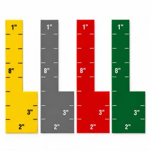 May include: Four L-shaped rulers in yellow, gray, red, and green. Each ruler features white printed markings and labels including 1 inch, 8 inches, 3 inches, and 2 inches. The rulers are arranged side-by-side, displaying clear measurement increments.