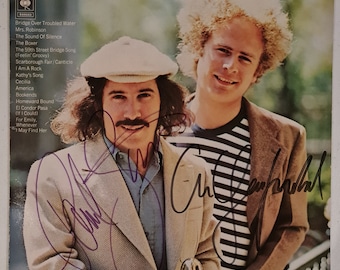 May include: A vintage vinyl record album cover featuring a photo of Simon and Garfunkel. The album title is "Simon and Garfunkel's Greatest Hits" and the record label is CBS. The album cover is signed by both Simon and Garfunkel.