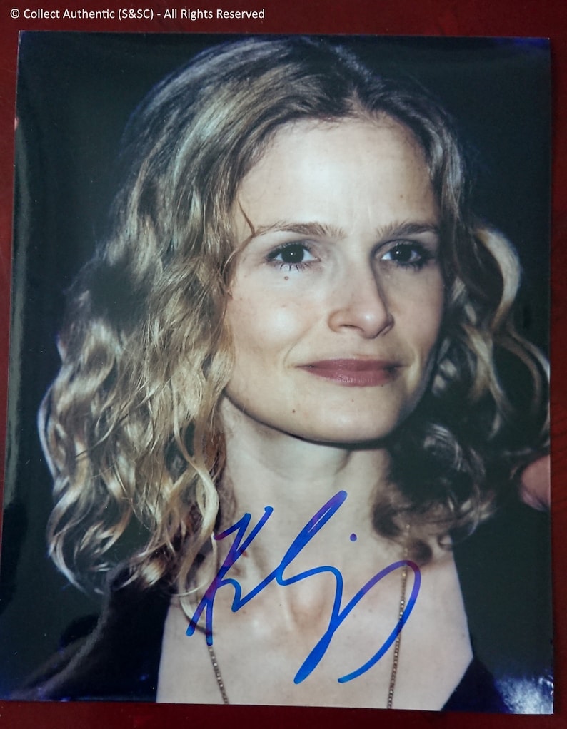 Puede incluir: Una foto de primer plano de una mujer con cabello rubio y ojos azules. Ella est&aacute; sonriendo y mirando a la c&aacute;mara. Su firma est&aacute; escrita en tinta azul debajo de su imagen.