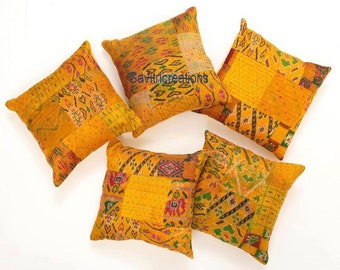 May include: Five yellow and orange patterned throw pillows with a kantha stitch design. The pillows are made from recycled saris and are perfect for adding a touch of bohemian style to your home.