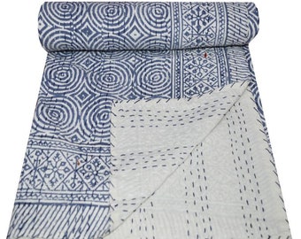 May include: A rolled-up quilt with a blue and white geometric pattern. The quilt displays circular and rectangular designs. The material appears soft, suggesting use as bedding or a decorative item. The quilt's dimensions are not visible.