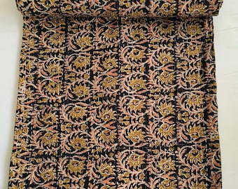 May include: Rolled-up black quilt with a repeating floral pattern in gold and peach. The quilt is made of a soft material and is suitable for a bed or sofa. The floral design is intricate and detailed.