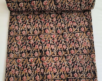 May include: Rolled-up, quilted textile featuring a repeating floral pattern. The design includes red flowers, brown stems, and leaves against a black background. The edges are neatly finished, showcasing the craftsmanship of the piece.