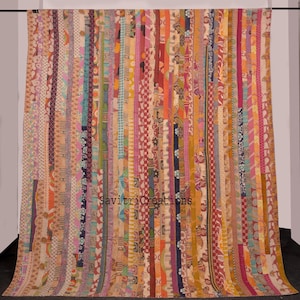 Puede incluir: Una colcha kantha colorida con un diseño de patchwork que presenta rayas verticales de varias telas y patrones. La colcha está hecha de saris reciclados y tiene un aspecto rústico y vintage.