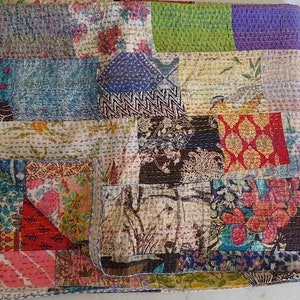 K&ouml;nnte beinhalten: Eine Patchwork-Decke mit einer Vielzahl von bunten Stoffen und Mustern. Die Decke besteht aus Quadraten und Rechtecken in verschiedenen Gr&ouml;&szlig;en und Farben. Die Decke ist aus Baumwolle und handgen&auml;ht.
