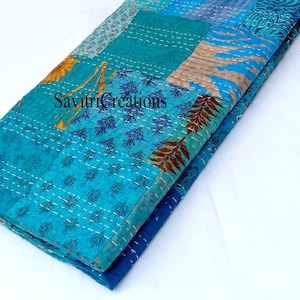 May include: A blue and brown patchwork quilt with a white stitching pattern. The quilt is folded in half and the fabric has a floral pattern.