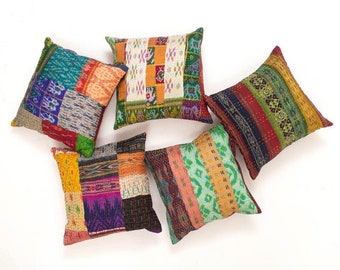 May include: Five square throw pillows featuring a patchwork design of various colorful fabrics. Each pillow displays a unique combination of patterns, including geometric shapes, stripes, and floral motifs in shades of red, blue, green, and yellow.