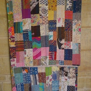 K&ouml;nnte beinhalten: Ein farbenfroher Patchwork-Deckenbezug aus verschiedenen Stoffen mit unterschiedlichen Mustern und Farben. Der Bezug besteht aus vielen kleinen Quadraten, die zusammengen&auml;ht wurden, um ein gr&ouml;&szlig;eres Design zu schaffen. Der Bezug h&auml;ngt an einer Wand.