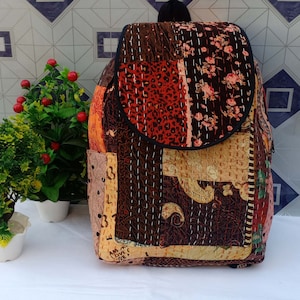 Könnte beinhalten: Ein brauner Patchwork-Rucksack mit Blumenmuster und einem Leopardenfell-Patch. Der Rucksack hat einen Klappverschluss und eine Reißverschlusstasche auf der Vorderseite. Der Rucksack ist aus gestepptem Stoff gefertigt und hat einen braunen Lederriemen.