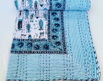 May include: A rolled-up, handmade quilt featuring a fish pattern in shades of blue and white. The quilt has a striped pattern on the right side and floral borders. The stitching is visible, adding to the handcrafted aesthetic.