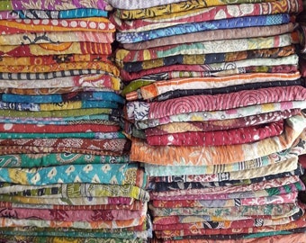 May include: A stack of colorful kantha quilts, made from recycled saris, with intricate embroidery and patchwork designs.