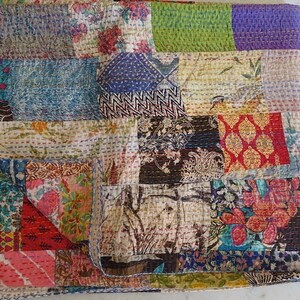 K&ouml;nnte beinhalten: Eine Patchwork-Decke mit einer Vielzahl von bunten Stoffen und Mustern. Die Decke besteht aus Quadraten und Rechtecken in verschiedenen Gr&ouml;&szlig;en und Farben. Die Decke ist aus Baumwolle und handgen&auml;ht.