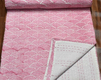 May include: Pink kantha quilt with a white background and a pattern of pink arches. The quilt is folded in half and the stitching is visible on the white side.