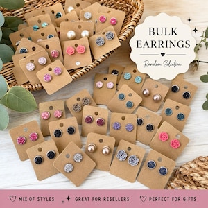 May include: A collection of assorted stud earrings mounted on individual brown cardboard display cards. The earrings feature various designs including solid spheres, textured glitter surfaces, and floral shapes in colors like pink, blue, black, and white.