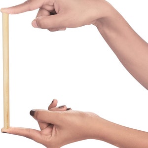 Puede incluir: Primer plano de una varilla de madera sostenida entre dos manos. La varilla es de color marr&oacute;n claro y parece ser lisa.
