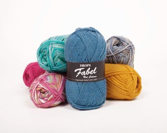 May include: A collection of colorful yarn balls, including teal, pink, yellow, and blue. The blue yarn ball has a label that reads "DROPS Fabel Uni Colour - Superwash treated sock wool."
