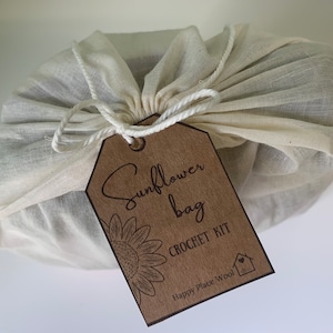 May include: A brown paper tag with the text "Sunflower Bag Crochet Kit" and the logo "Happy Place Wool" is tied to a white muslin bag.