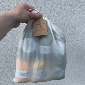 May include: A white cotton drawstring bag with a brown tag that says "Sunflower Bag Crochet Kit Happy Place Wool". The bag contains yarn skeins.