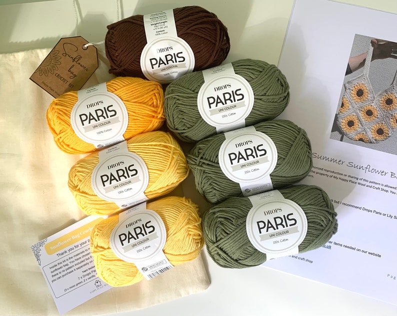 May include: A set of yarn for crocheting a sunflower bag. The yarn is in shades of yellow, green, and brown. The yarn is labeled "DROPS PARIS UN COLOUR 100% Cotton".