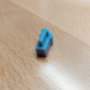 May include: A small, light blue plastic keycap with a raised, rectangular shape.