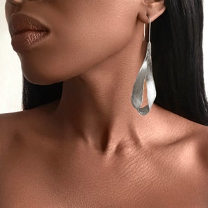 May include: Silver dangle earrings with a unique, twisted, teardrop shape.