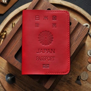 以下が含まれることがあります： 前面に「JAPAN PASSPORT」の文字が刻印された赤い革製の旅券カバー。カバーには日本の印章と日本語で「日本国旅券」の文字が刻印されています。