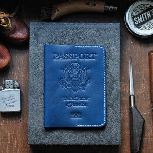 May include: A blue leather passport holder with the words "PASSPORT", "United States of America", and an embossed image of the American eagle.