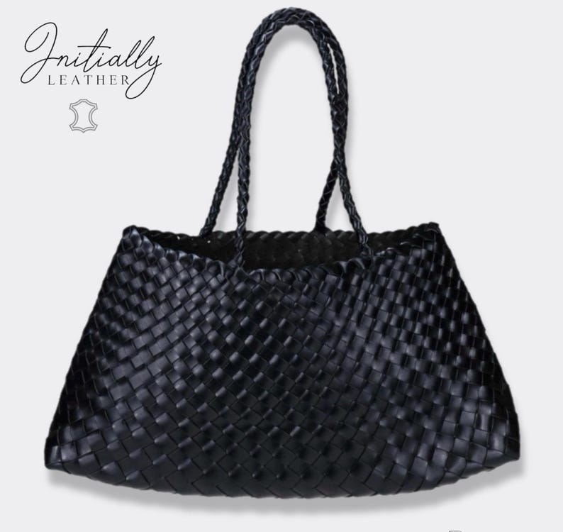 May include: A black woven leather tote bag with braided handles. The bag has a trapezoid shape and a textured surface. The brand name "Initially Leather" is displayed in cursive script on the upper left corner.
