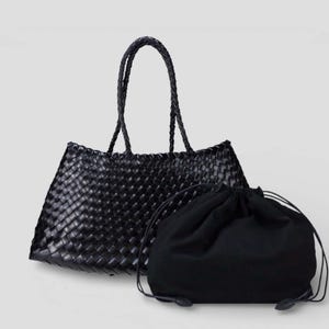 May include: A black woven tote bag with braided handles and a matching drawstring bag. The tote bag has a rectangular shape with a woven pattern. The drawstring bag is made of a soft, dark fabric.