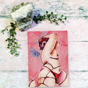 Peut inclure: Une illustration à l'aquarelle d'une personne avec une auréole et des ailes, attachée avec des cordes, sur un fond rose avec des paillettes.