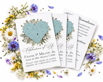 Könnte beinhalten: Ein Set weißer Gedenkkarten mit einem strukturierten hellblauen Herz aus Samenpapier, umgeben von grünen botanischen Illustrationen. Der Text lautet Celebration of Life, Frank P. Miller Jr., 10. April 1990 - 7. März 2026.