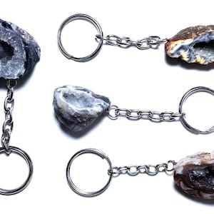 May include: Four agate geode keychains with silver key rings and chains. The geodes are various shades of gray, white, and brown with a crystal interior.