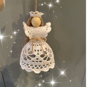Op de afbeelding: Witte gehaakte engelversiering met een houten hoofd en een kroon. De engel hangt aan een touwtje.
