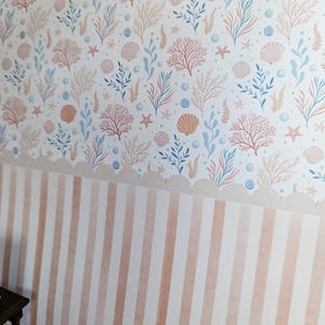 May include: A patterned wallpaper design featuring a nautical theme. The upper portion showcases a repeating pattern of seashells, coral, and seaweed in shades of peach, blue, and beige against a white background. The lower section has vertical peach and white stripes.