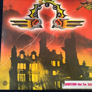 May include: Album cover art with a dramatic, stylized design. The word "MEGA" is arched across the top, with lightning bolts and a silhouetted cityscape below. The background is a gradient of red and orange.