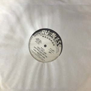 以下が含まれることがあります： 「Ruthless Records」の文字と「Panic Zone」や「Dope Man」などの曲名が記載された黒いレコード。白い紙のスリーブに入っています。