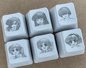 May include: Six grey keycaps with black and white illustrations of anime characters. Each keycap features a different character with a unique hairstyle and expression.